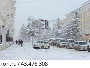 Заснеженная городская улица. Много снега на проезжей части, тротуаре, машинах и деревьях. Холодная снежная погода. Снегопад в городе. Магадан, Магаданская область, Россия. Редакционное фото, фотограф Андрей Степанов / Фотобанк Лори