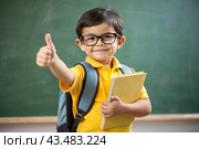 A boy with glasses shows the class with his hand. The child goes to school for the first time. A child with a school bag and a book. A child in the classroom on the background of a blackboard. Back to school. Стоковое AI-изображение, AI-художник Photojuli / Фотобанк Лори