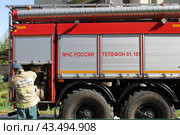 Сотрудник МЧС России пожарного расчета около пожарной машины во время тушения пожара. Стоковое фото, фотограф Людмила Ефимова / Фотобанк Лори