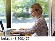 A businesswoman in glasses works on a laptop near the window. Стоковое фото, фотограф Alexandra Aleroewa / Фотобанк Лори