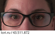 Close-up of a young adult Caucasian brunette woman looking at the camera and putting on glasses. Ophthalmology and vision impairment concept. Стоковое видео, видеограф Денис Кебедов / Фотобанк Лори