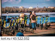 Люди в пуховиках подключаются к самокатам (2021 год). Редакционное фото, фотограф Илья Старков / Фотобанк Лори