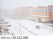 Snowfall in the city. Top view of a snowy city street and colorful buildings. Car rides on a road covered with snow. Anadyr, Chukotka, Siberia, Far East of Russia. October in the Arctic. (2009 год). Стоковое фото, фотограф Андрей Степанов / Фотобанк Лори