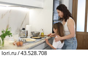Happy mother and her preteen daughter frying pancakes on stove in the kitchen. Стоковое видео, видеограф Яков Филимонов / Фотобанк Лори