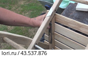 Restoration and repair of a wooden vintage chair. The man tries on a metal plate to strengthen the structure. The chair lies on a workbench. Close-up. Стоковое видео, видеограф Vadzim Yakubovich / Фотобанк Лори