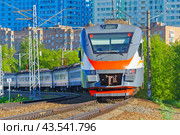 Passenger electric train moves against the background of green trees and city houses. Стоковое фото, фотограф Михаил Строгалев / Фотобанк Лори