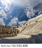 Roman Theatre in Amman, Jordan -- theatre was built the reign of Antonius Pius (138-161 CE), the large and steeply raked structure could seat about 6000 people. Against the sky with clouds (2016 год). Стоковое фото, фотограф Владимир Журавлев / Фотобанк Лори