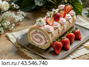 Swiss sponge roll with strawberries, a delicious fruit and cream dessert filled with cream cheese, decorated with fresh strawberries. Стоковое AI-изображение, AI-художник Photojuli / Фотобанк Лори