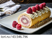 Swiss sponge roll with raspberries, a delicious fruit and cream dessert filled with cream cheese, decorated with fresh raspberries. Стоковое AI-изображение, AI-художник Photojuli / Фотобанк Лори