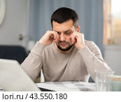 Man rubs tired eyes with his hands after a long work at laptop at home. Стоковое фото, фотограф Яков Филимонов / Фотобанк Лори