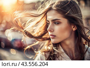 A beautiful, young woman with a thoughtful look. The hair develops in the wind and gives a feeling of lightness and naturalness. Стоковое AI-изображение, AI-художник Photojuli / Фотобанк Лори