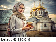 The concept of the Russian Orthodox holiday Honey Savior. A beautiful girl in Russian national clothes and a scarf with a jar of honey on the background of an Orthodox church. Стоковое AI-изображение, AI-художник Photojuli / Фотобанк Лори
