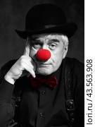 Dramatic selective color portrait of a sad clown against a dark background. Hand near face. Стоковое фото, фотограф Сергей Пристяжнюк (Serg Zastavkin) / Фотобанк Лори