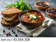 Combined meat hodgepodge with black bread and herbs in a ceramic tureen plate close-up. Стоковое AI-изображение, AI-художник Photojuli / Фотобанк Лори