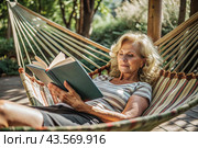 An elderly pensioner, a modern grandmother with glasses, reads a book on vacation in a hammock by the sea in natural light. Стоковое AI-изображение, AI-художник Photojuli / Фотобанк Лори