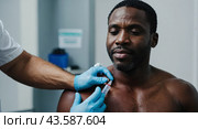 A man receives a vaccine shot in his shoulder, administered by a healthcare professional wearing gloves. Стоковое AI-изображение, AI-художник Tatiana Syrtseva / Фотобанк Лори