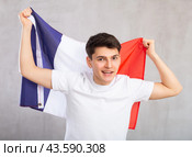 Happy young man holding flag of France against unicoloured background. Стоковое фото, фотограф Яков Филимонов / Фотобанк Лори
