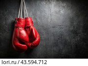 Professional red boxing gloves hang on a black background with a space to copy. Стоковое AI-изображение, AI-художник Photojuli / Фотобанк Лори