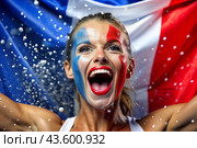 A beautiful athlete or cheerleader from France with joyful shouts after winning the competition at the Olympic Games against the background of the French flag. Стоковое AI-изображение, AI-художник Photojuli / Фотобанк Лори
