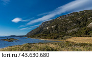 Yellowed grass grows on the shore of a blue lake. Tiny islands in the water. A picturesque mountain against an azure sky and clouds. Tierra del Fuego National Park. Lapataia Bay. Patagonia. Argentina. Стоковое фото, фотограф Вера Ивановна Кубарева / Фотобанк Лори