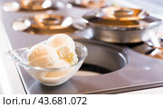 Glass dessert bowl with vanilla ice cream on the table in the display case for distribution. Стоковое фото, фотограф Татьяна Яцевич / Фотобанк Лори