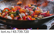 A large wok filled with a variety of fresh vegetables is currently cooking on a stove. Стоковое AI-видео, аниматор Юрий Поздников / Фотобанк Лори