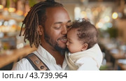 A joyful man gently holds a lovely baby in a comfortable carrier, radiating pure happiness. Стоковое AI-видео, аниматор Юрий Поздников / Фотобанк Лори