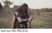 Medieval knight kneels in prayer in field. Стоковое видео, видеограф Илья Шаматура / Фотобанк Лори