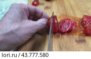 Men's hands are slicing cherry tomatoes on a wooden board with a large kitchen knife. Стоковое видео, видеограф Ярославский Максим / Фотобанк Лори