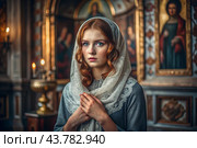 Portrait of a beautiful young woman in a headscarf in an Orthodox church. A girl prays in a church against the background of icons. Стоковое AI-изображение, AI-художник Photojuli / Фотобанк Лори
