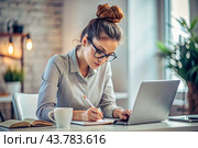A young female freelance businessman in glasses and headphones is working on a laptop or shopping in an online store. The woman is writing something in a notebook. Стоковое AI-изображение, AI-художник Photojuli / Фотобанк Лори