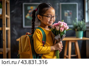 A first-grader Asian girl with glasses at the blackboard. The girl has flowers in her hands. The child goes to school for the first time. A child with a backpack, a book and flowers. Back to school. Стоковое AI-изображение, AI-художник Photojuli / Фотобанк Лори