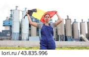 Sad young woman worker standing with big flag of Belgium against background of factory. Стоковое видео, видеограф Яков Филимонов / Фотобанк Лори