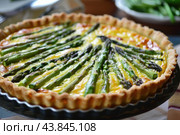 Fresh asparagus quiche on table. Стоковое AI-изображение, AI-художник Иван Рябоконь / Фотобанк Лори