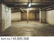 Dimly lit, deserted basement parking with peeling paint and concrete columns. Стоковое AI-изображение, AI-художник Иван Рябоконь / Фотобанк Лори