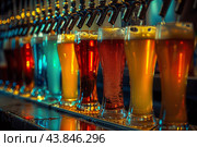 Bartender pouring fresh craft beer from taps in a row at pub. Стоковое AI-изображение, AI-художник Иван Рябоконь / Фотобанк Лори