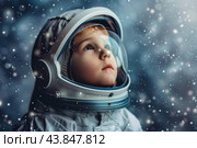 Little astronaut wearing space suit looking up at falling snow. Стоковое AI-изображение, AI-художник Иван Рябоконь / Фотобанк Лори