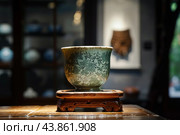 Antique chinese green celadon porcelain cup sitting on wooden pedestal. Стоковое AI-изображение, AI-художник Иван Рябоконь / Фотобанк Лори