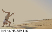 A man is showing martial arts - capoeira - on the beach at sunset. Стоковое видео, видеограф Константин Шишкин / Фотобанк Лори