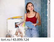Young woman with palette of colors in hands selects harmonious color of paint with existing tiles. Стоковое фото, фотограф Яков Филимонов / Фотобанк Лори