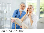 Satisfied old woman patient holding mirror sitting on clinical chair. Стоковое фото, фотограф Яков Филимонов / Фотобанк Лори