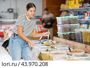 Girl in supermarket scooping marinated green olives into plastic bag. Стоковое фото, фотограф Яков Филимонов / Фотобанк Лори