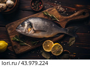 Delicious and healthy fish. Raw dorado with lemon and ingredients on a dark background. Banner, menu, place for recipe text, top view. Стоковое AI-изображение, AI-художник Photojuli / Фотобанк Лори
