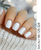 Elegant white manicure with glitter accent on a cozy sweater background. Стоковое AI-изображение, AI-художник Юлия Гапеенко / Фотобанк Лори