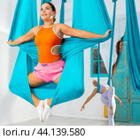 Young women making antigravity yoga exercises with group of people. Стоковое фото, фотограф Яков Филимонов / Фотобанк Лори