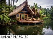 Tranquil waterside cabin with traditional thatched roof amidst lush greenery. Стоковое AI-изображение, AI-художник Иван Рябоконь / Фотобанк Лори