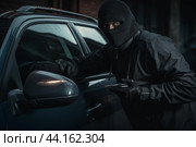Masked burglar attempting car theft at night. Стоковое AI-изображение, AI-художник Иван Рябоконь / Фотобанк Лори