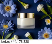 A jar of face cream with a gold lid on a dark blue background surrounded by wild white and blue flowers. Стоковое AI-изображение, AI-художник Ольга Пахомова / Фотобанк Лори