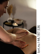 Close-up of woman masseur doing medical back backbone massage of lady patient in dark medical spa room in shadow. Rehab massage, healthy relax massaging. Wellness, health concept. Copy ad text space. Стоковое фото, фотограф Aleksandr Golubev / Фотобанк Лори
