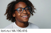 Portrait of a happy dark skinned schoolboy teenager with glasses on a solid gray background. Back to school, correction of pupil kid eyesight. AI generated. Стоковое AI-изображение, AI-художник Ольга Симонова / Фотобанк Лори